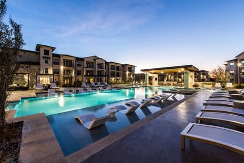 a large swimming pool with lounge chairs at dusk